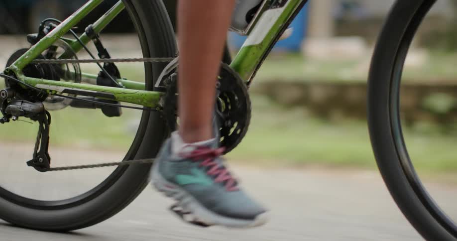 Bicyclist pushes the pedals as he rides down the street
