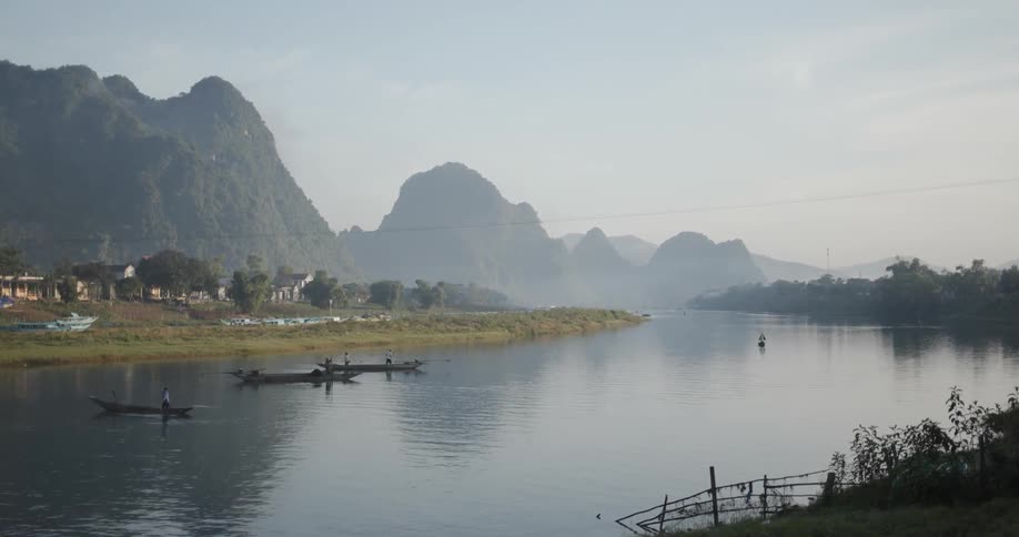 Canoes float in the river under a blue sky