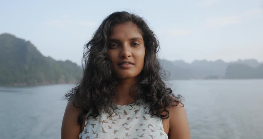 A woman is looking forward by the water smiling