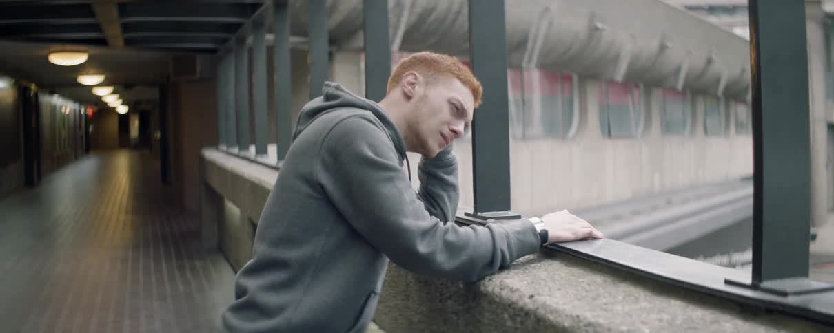 Man leans looking over the ledge of a concrete building