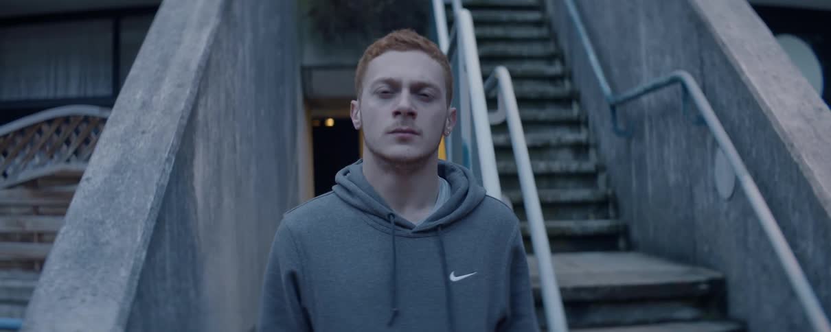 Exhausted looking man stands outside and rolls his shoulders