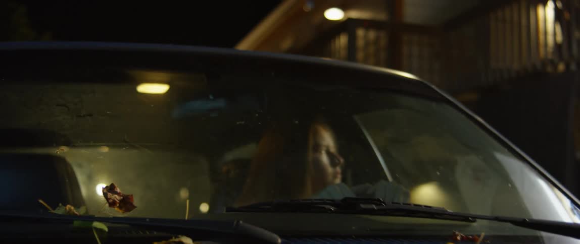 Woman sits in a car in the city at night
