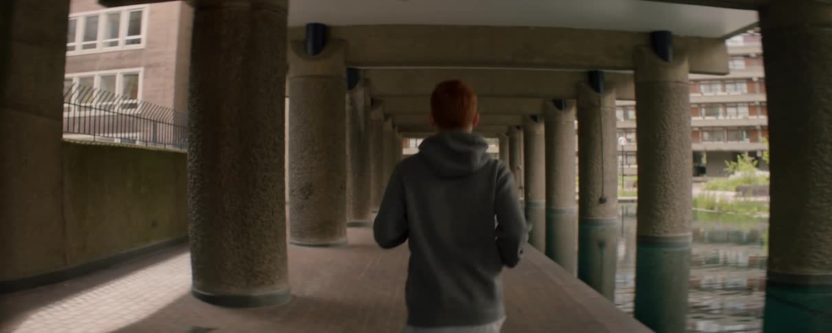 A man is jogging near a reflecting pool in a city in daylight