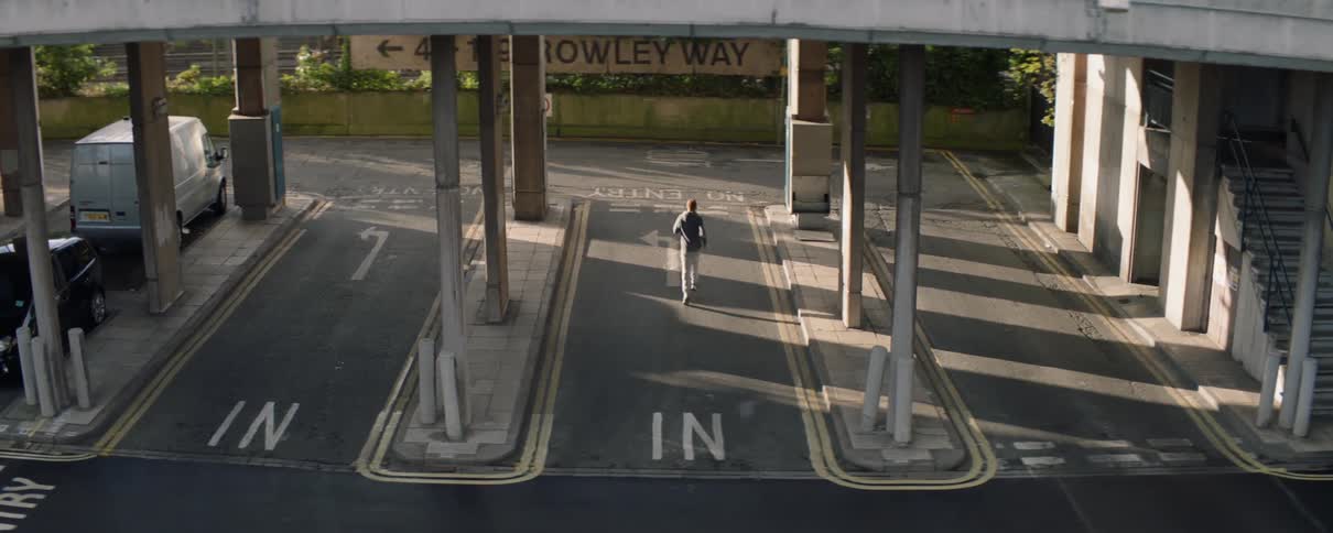 Man runs in a parking lot under a bridge