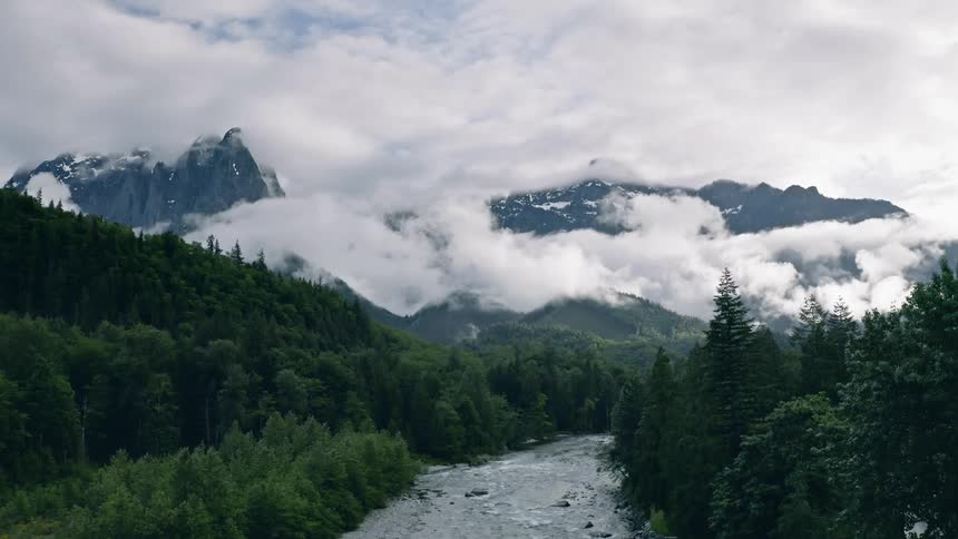 Clouds pass above and between mountains - 4K Aerial