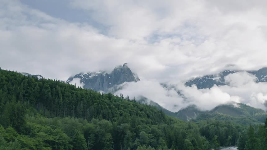 The clouds move over the mountain by the stream - 4K Aerial