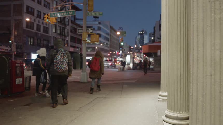 People are walking on street sidewalk in city at night