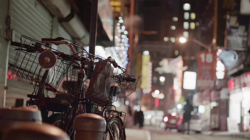 Bicycles are parked next to a pole in a city at night