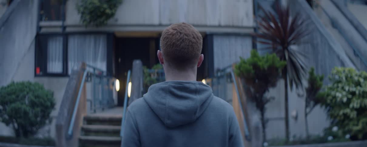A redheaded man loosens his neck outside