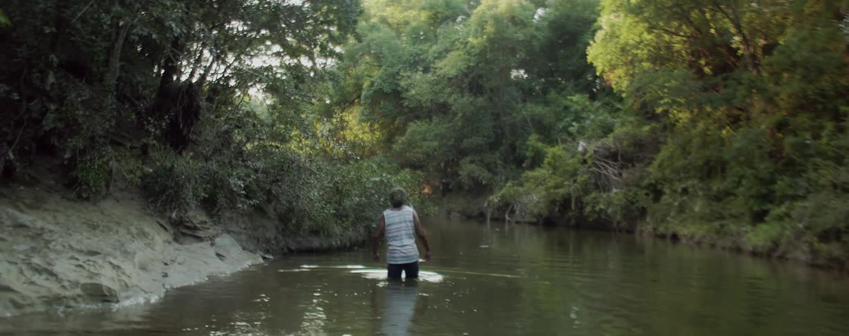 A man wades through the water in the pond