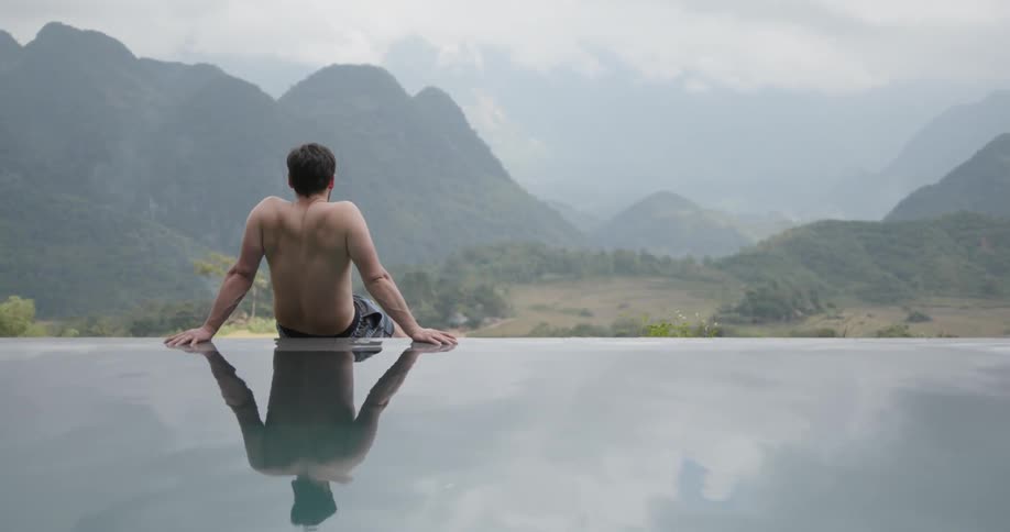 Man sits at the edge of a waterfall