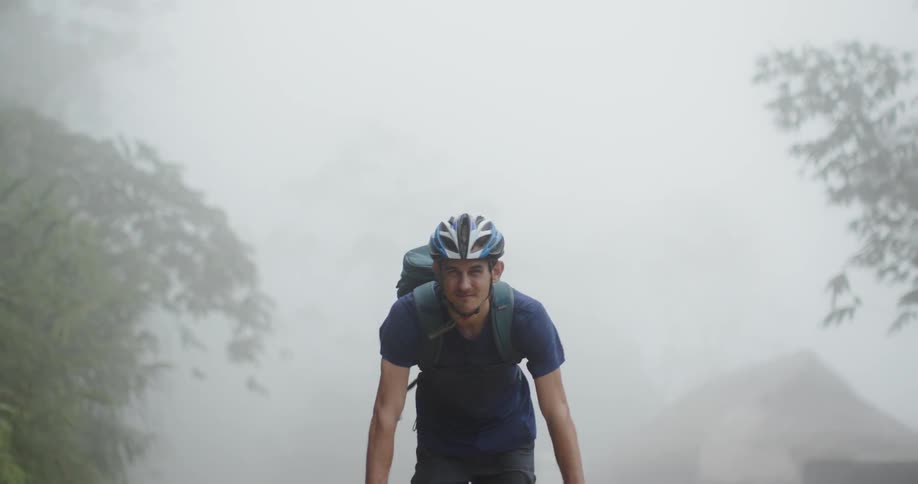 Man wearing a helmet rides his bike though the mist
