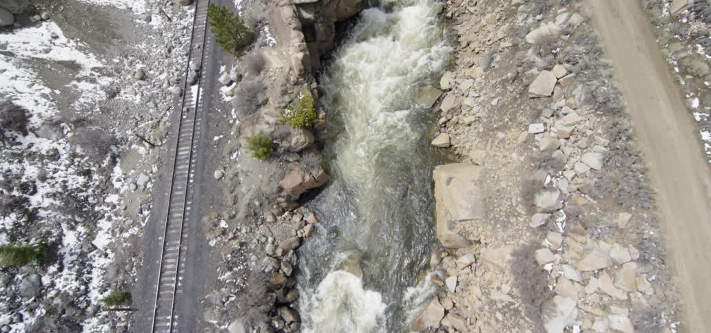 Stream waters flow next to railroad tracks