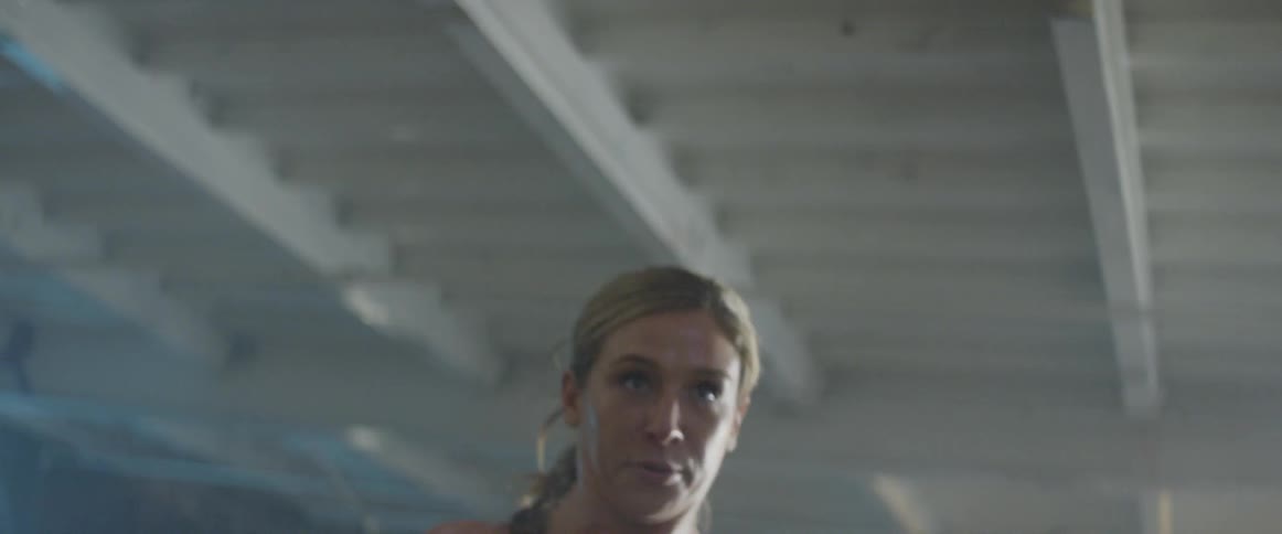 Woman lifts weights in a building with graffiti