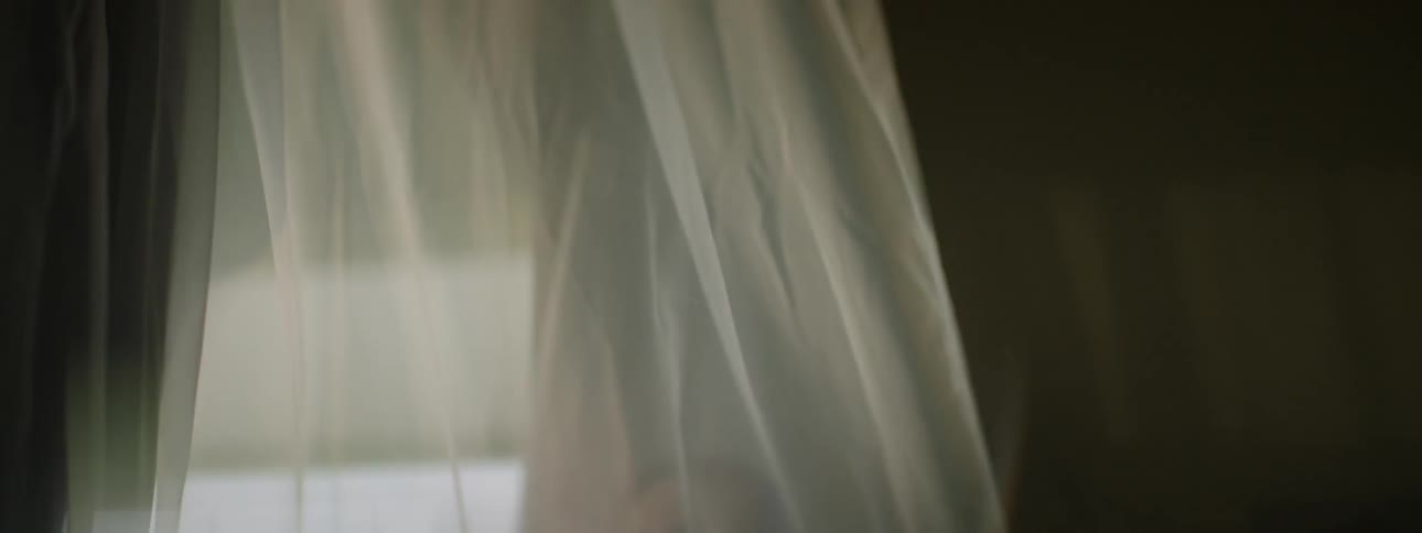 Woman is standing in home behind wind blown curtain