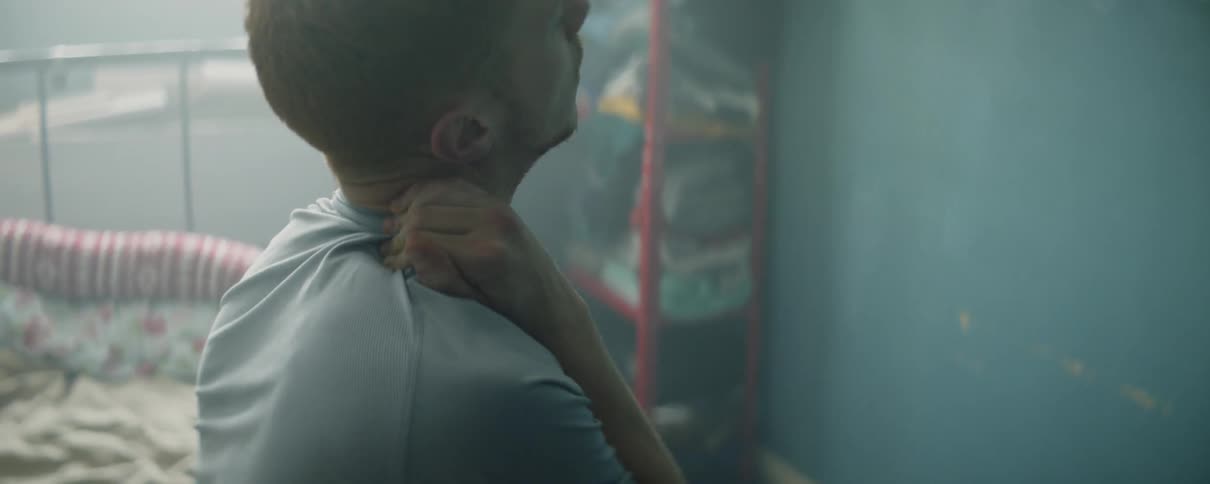 A man stretches his neck in bed