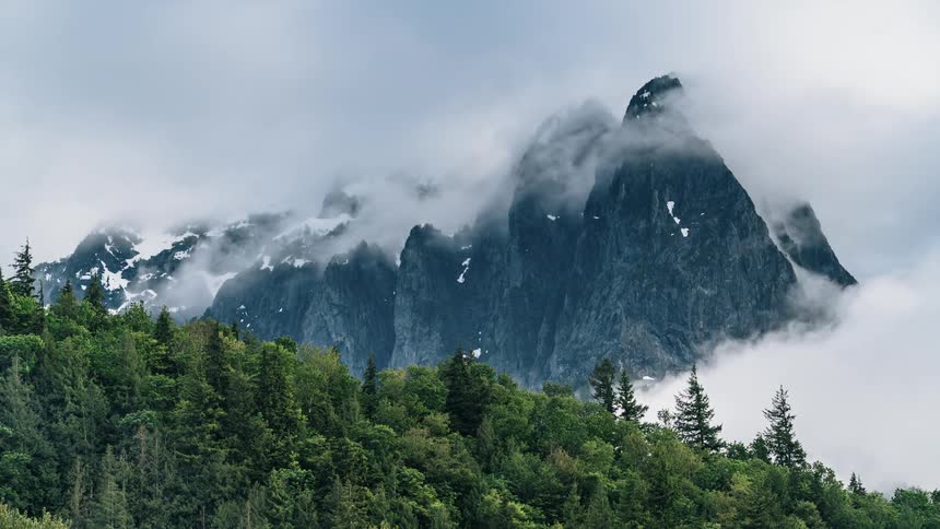 Clouds are floating and hovering near forest and mountains - 4K Time Lapse