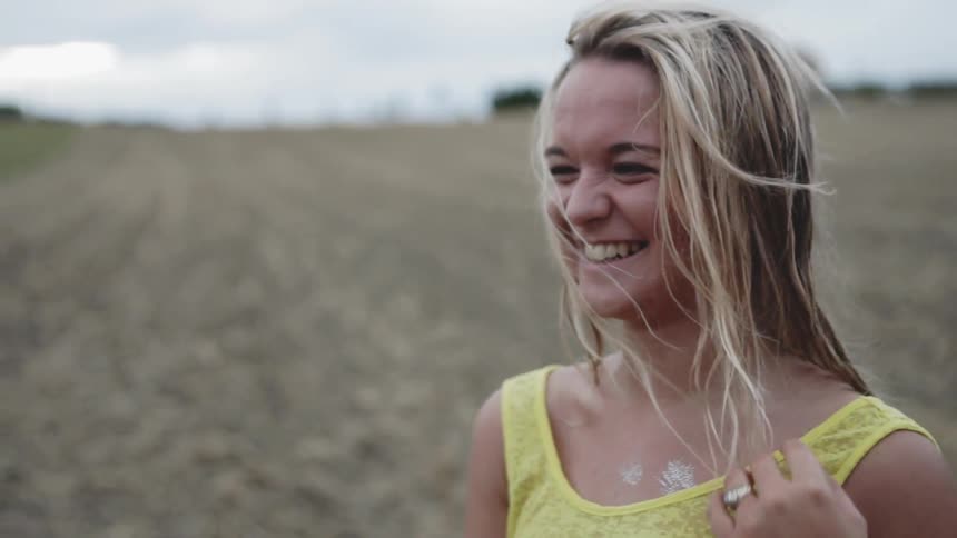 Woman pushes the hair away from her face as she stands in a field