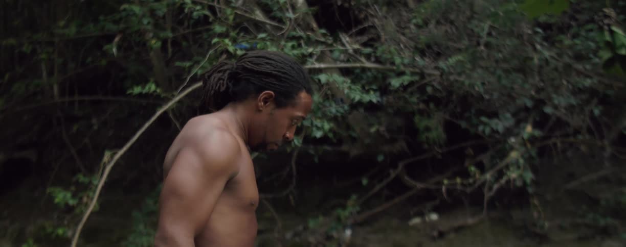 A shirtless man takes off his cap