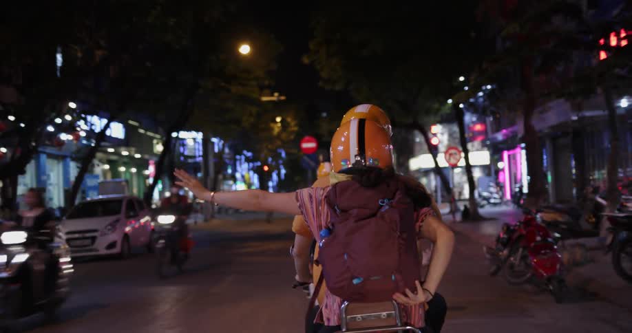 Man and woman ride a scooter on a city street