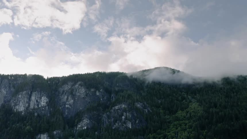 Clouds float above a mountain ridge - 4K Aerial