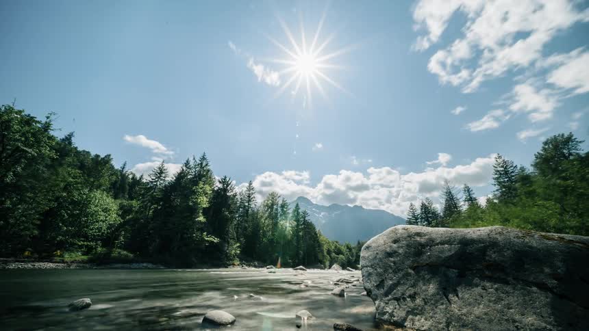 The sun is rising high above the large stream