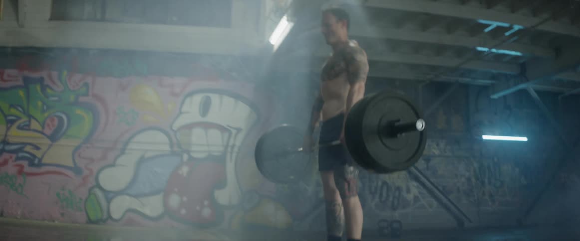 Man lifts weights in a building with graffiti