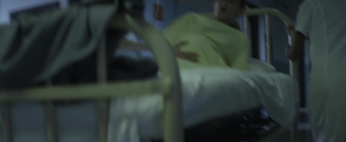 Medical staff wheel a bed with a pregnant woman down a hall