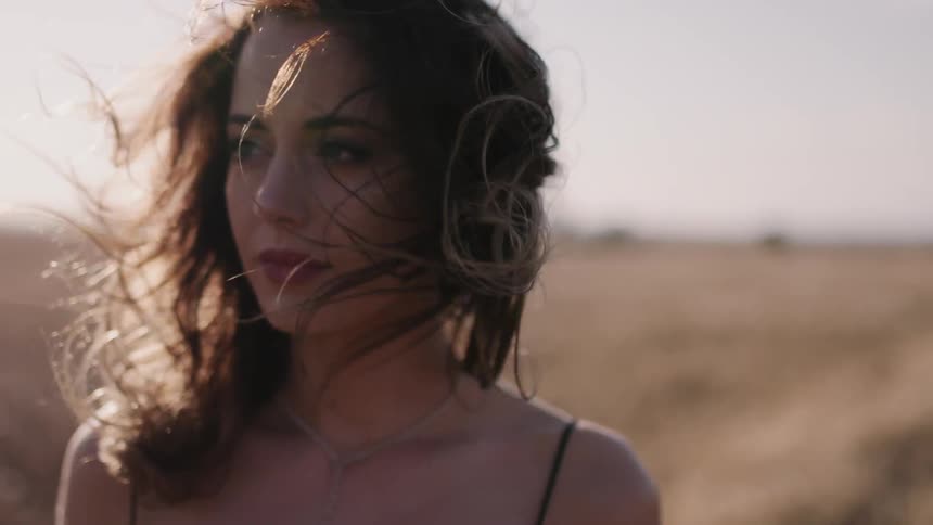 Woman walking through field on windy day