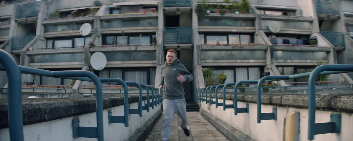 Man runs down a bridge a stops and doubles over