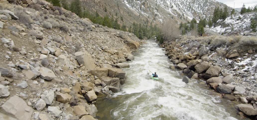 A person kayaks on a mountain river