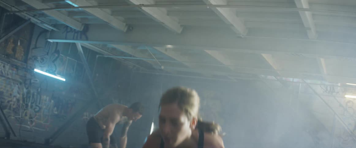 A woman and man lift weights in a gym