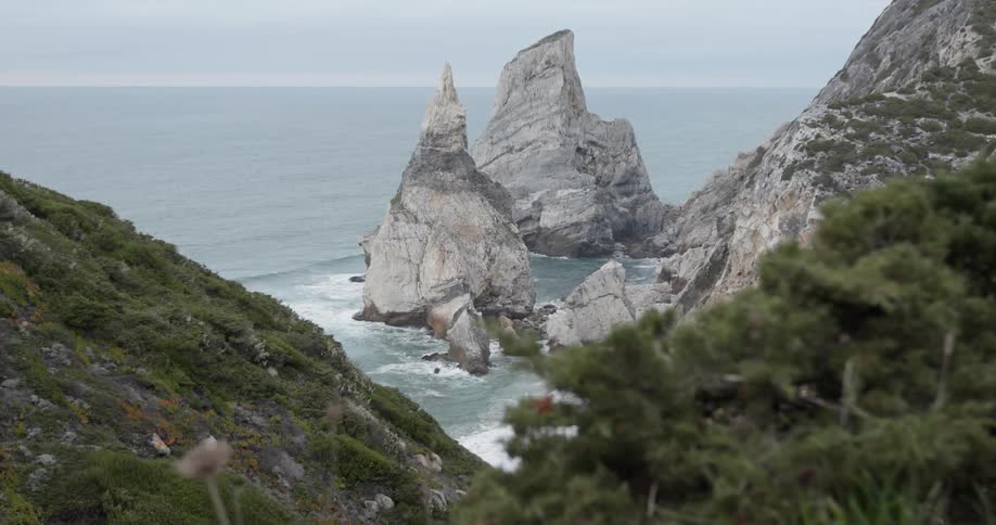 The waves hit the rocks on the foggy shore