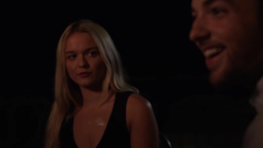 Woman watches a man talk in the dark