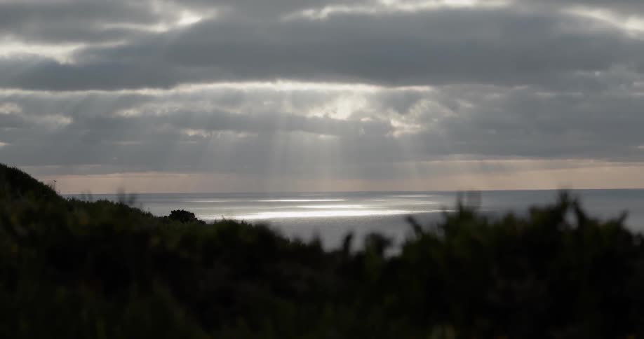 Sunlight is shining through clouds over ocean water