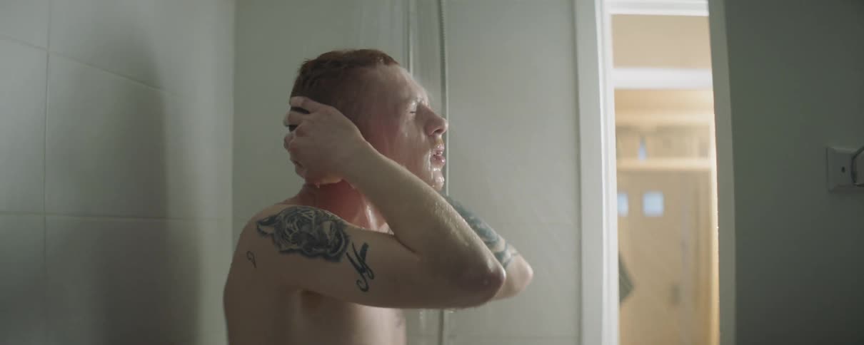 A man is taking a shower in a locker room during the day