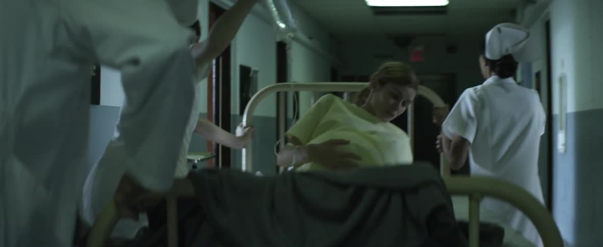 Doctors and nurses push a laboring woman on a gurney