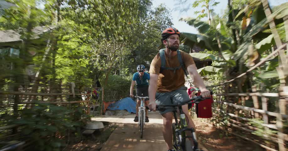 People ride their bikes down the sunny trail
