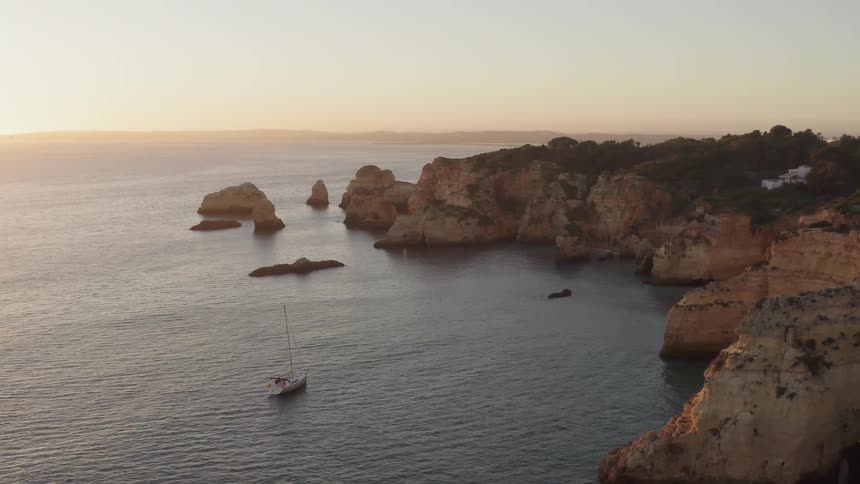 Boat floating on ocean coast near large rock formations