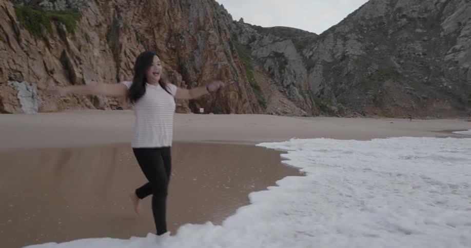 A woman runs as the tide flows on shore