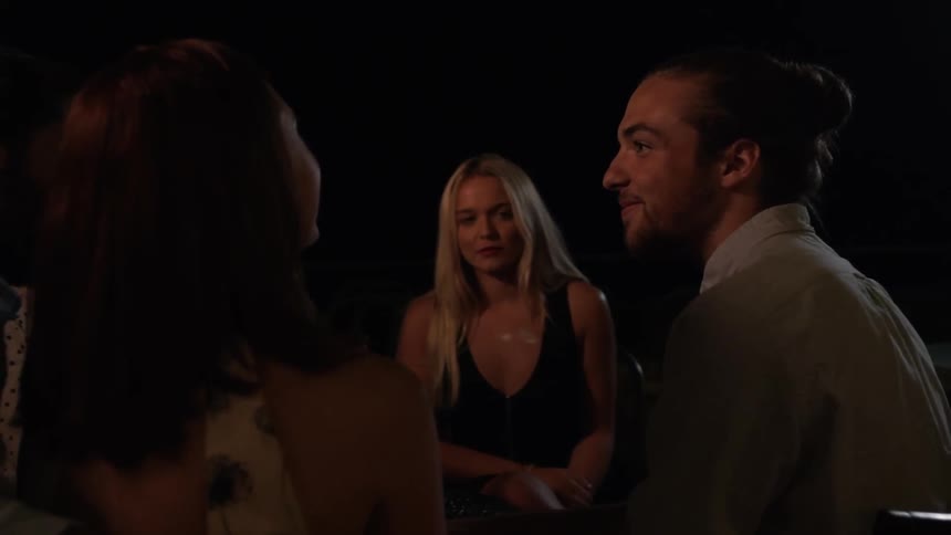 A man is laughing and talking as he sits outside at night with friends