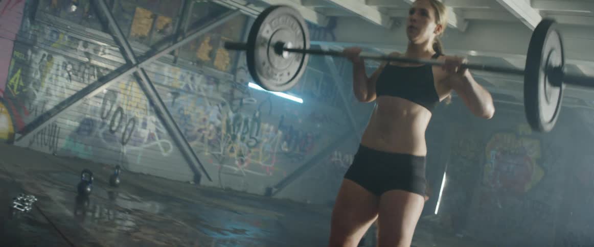 A woman lifts weights inside a dark gym