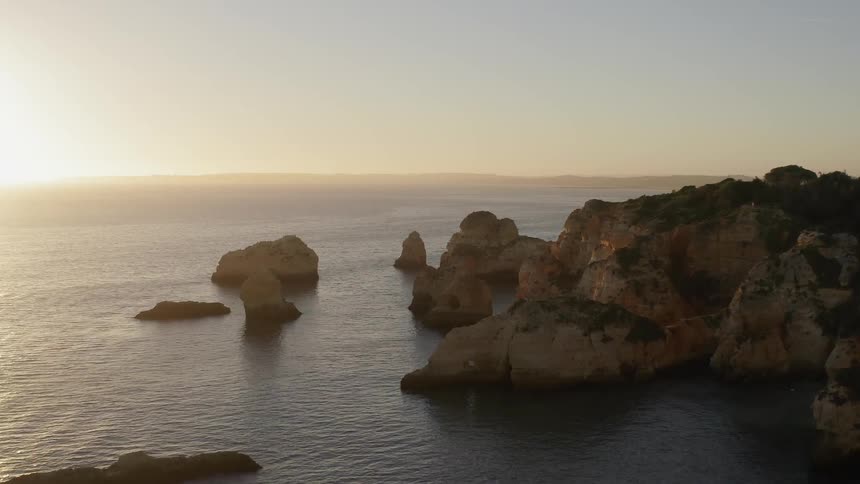 Large rock formations in the water on ocean coast at sunset