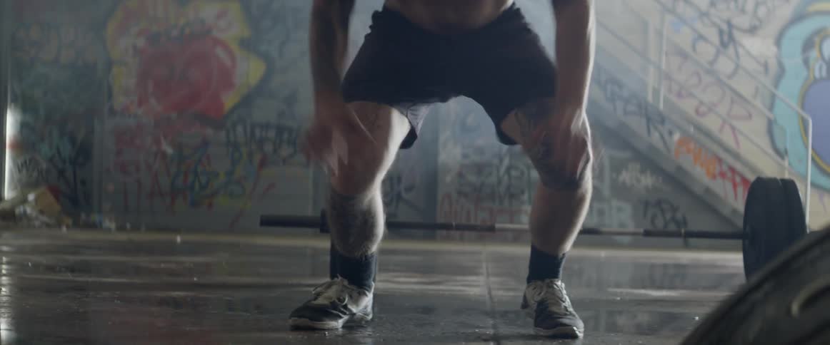 A man is doing pushups on a wet floor in daylight