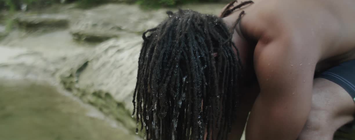 Man sits by river washing hair