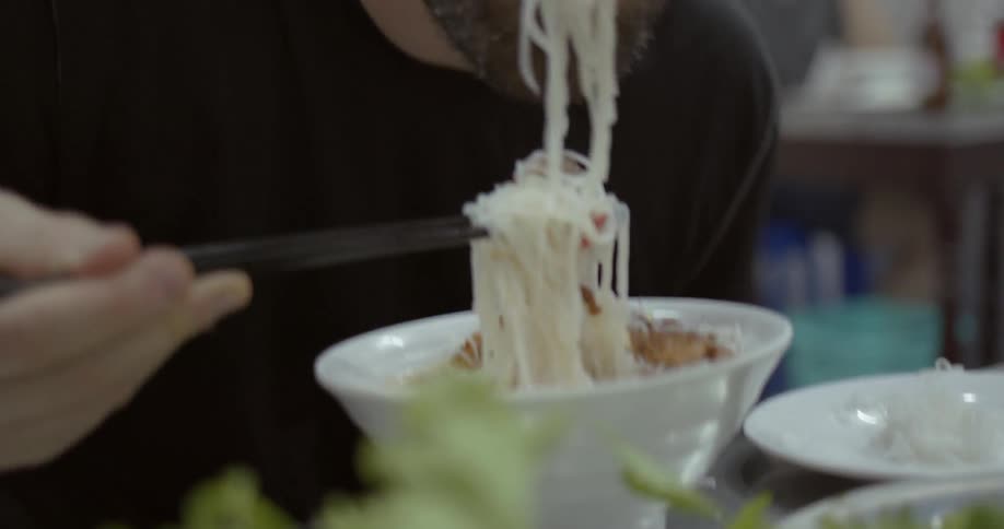Man eats noodles with chopsticks