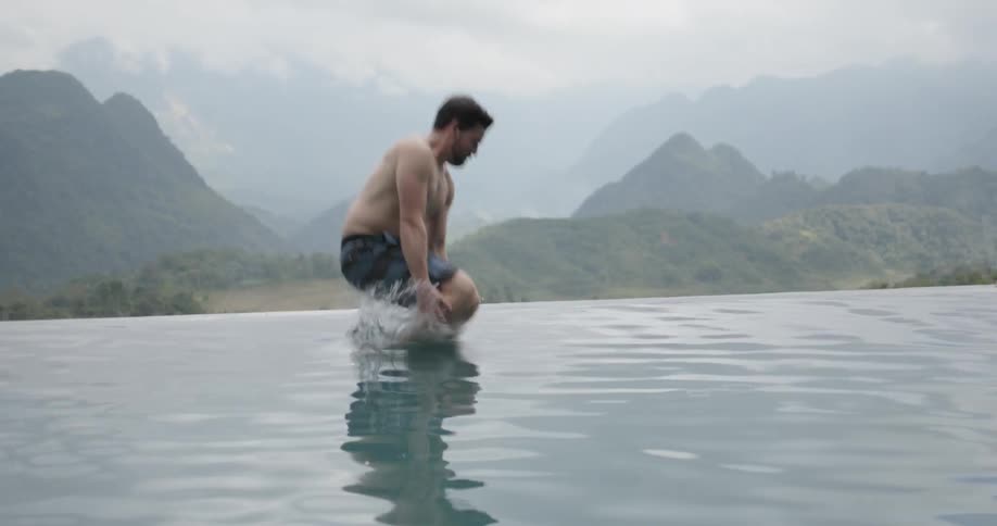 Man jumps into a swimming pool in the mountains