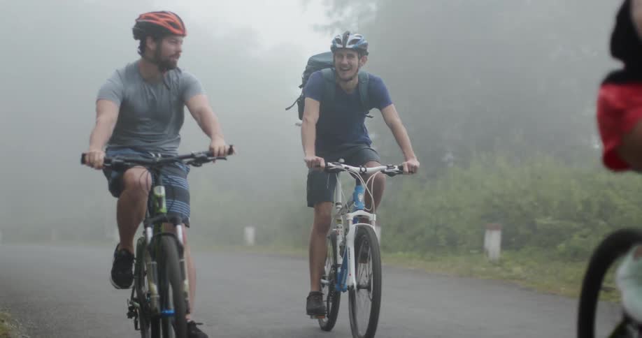 Bicyclists travel down a road surrounded by mist