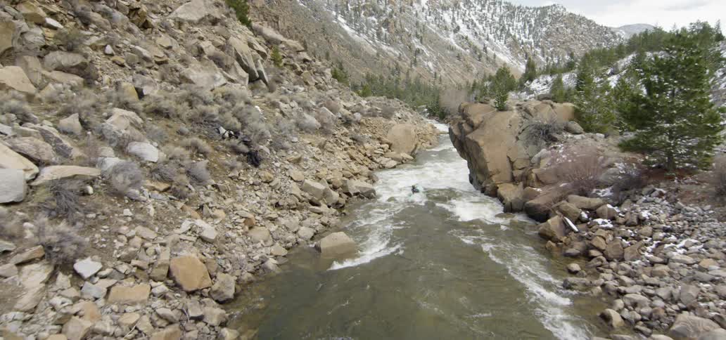 Water flows quickly in a stream surrounded by rocky terrain