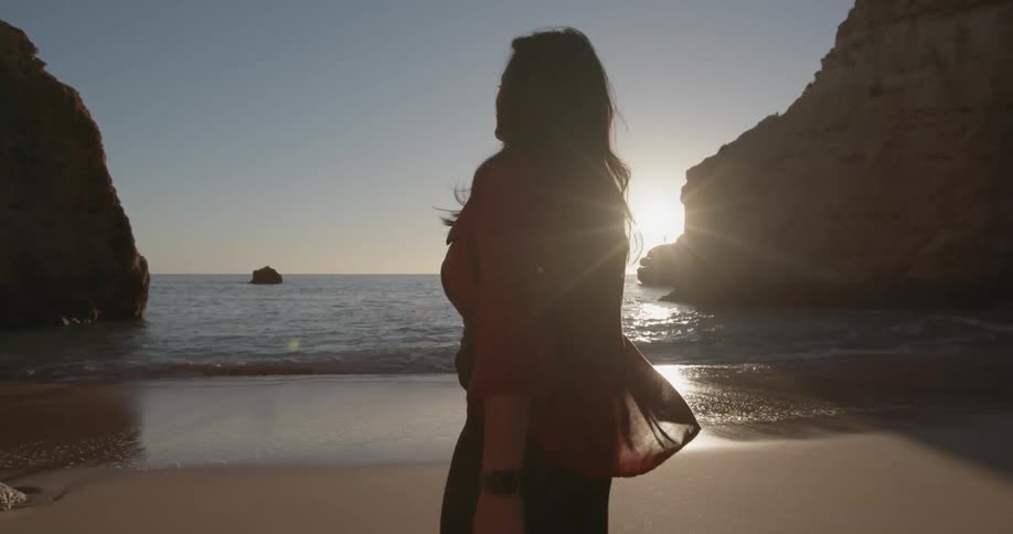 Woman walks on a beach at sunset